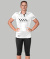 A woman wearing a white collared polo with black geometric patterns on the front, paired with black leggings. She is posing with her hands on her hips.